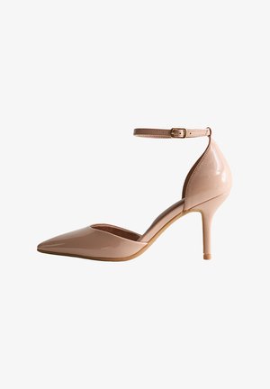 Nude patent leather pump with pointed toe, ankle strap, 4-inch stiletto heel, and smooth texture. Minimalist design with a sleek silhouette.