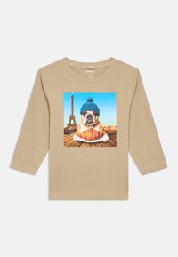 Camisa de mangas longas bege com uma impressão de um bulldog a usar um chapéu de malha azul, segurando um prato de croissants, com a Torre Eiffel ao fundo.