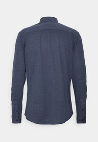 Långärmad skjorta i mörk marinblått tyg, har en krage med knappar, knappmanschetter och en rundad fåll med en slät textur.