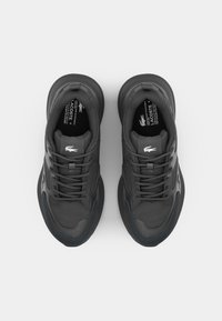 Black athletic shoes with a textured fabric upper, padded collar, and rubber outsole. Features laces and a subtle logo.