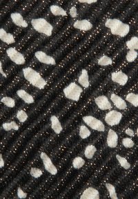 Tessuto con sfondo nero caratterizzato da forme bianche irregolari e accenti metallici dorati, che mettono in evidenza un motivo testurizzato.