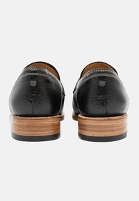 Scarpe in pelle nera con finitura testurizzata, dotate di tacco in legno sovrapposto e dettagli di cucitura a contrasto.