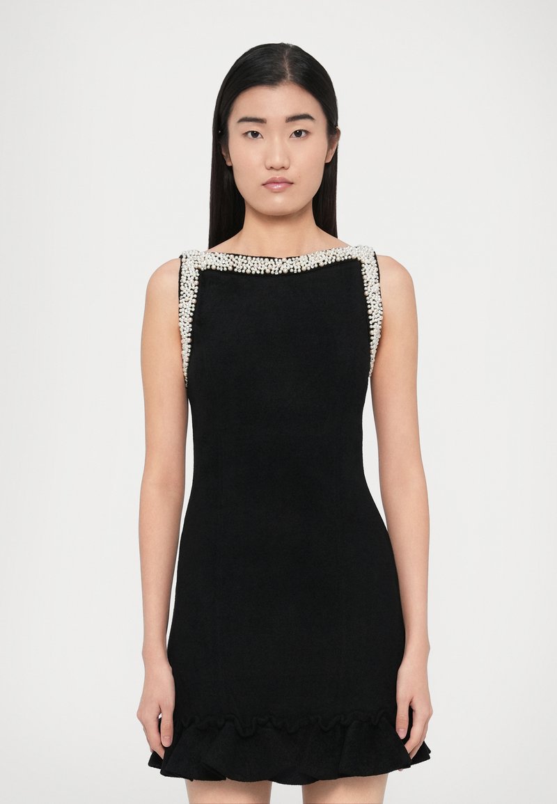 Svart ärmlös klänning med fyrkantig urringning, dekorerade axlar med pärlor och en volangprydd fåll. Tyget verkar mjukt med en slät textur.