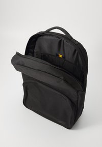 Sac à dos noir en tissu durable, avec un grand compartiment principal, une poche frontale et une poignée supérieure pour un transport facile.