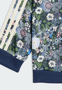 Kvetinová bomber bunda v námorníckej modrej farbe, zdobená živým viacfarebným vzorom s rebrovanými manžetami a tromi krémovými pruhmi na rukávoch.