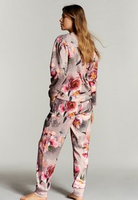 Loungewear set met bloemenpatroon in roze en grijstinten; bevat een langarmtop en bijpassende broek met elastische boorden.