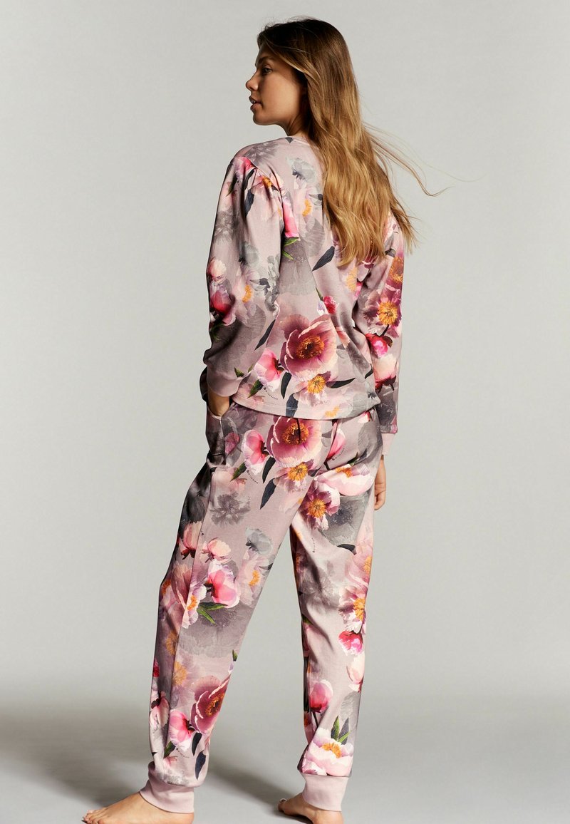 Loungewear set met bloemenpatroon in roze en grijstinten; bevat een langarmtop en bijpassende broek met elastische boorden.