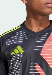 Maglia atletica nera con motivi astratti in grigio, bianco e rosa. Design a V con dettagli verdi; include il logo sulla spalla.