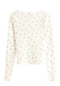 Ljust färgad långärmad topp med ribbat mönster, prydd med ett spritt blått rosettmönster och en rund halsringning.