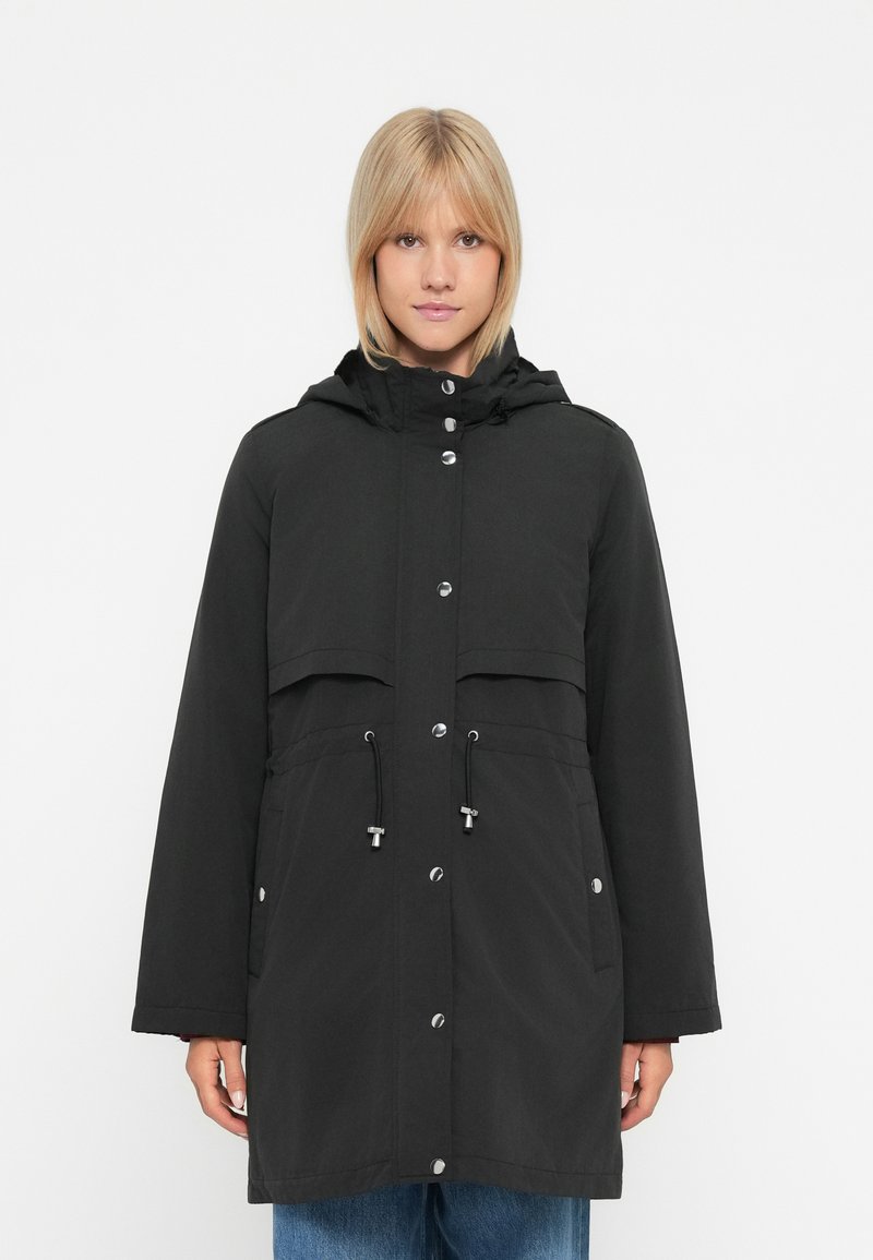Giacca nera impermeabile con cappuccio, chiusura frontale a bottoni, vita regolabile con cordino e due grandi tasche applicate. Texture liscia e design casual.