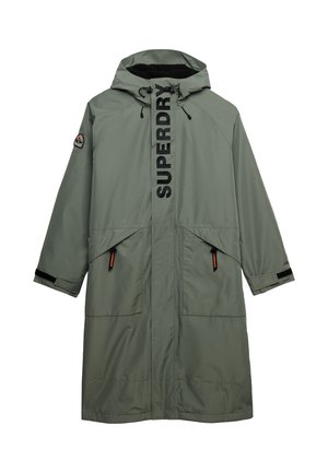 Długi oliwkowozielony płaszcz z kapturem, z przednimi kieszeniami, czarnym napisem "SUPERDRY" na klapie zamka i naszywką z logo na lewym rękawie.