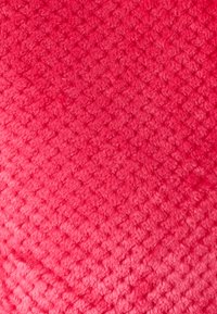Tessuto testurizzato di un vivace colore rosa, con un motivo a diamante. La superficie appare morbida con una texture pelosa.