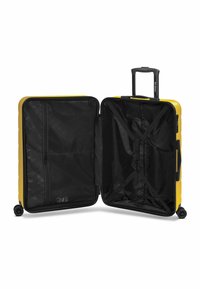 Maleta dura amarilla con interior negro, bolsillo frontal con cremallera, correas para asegurar el contenido y un mango retráctil. Cuatro ruedas.