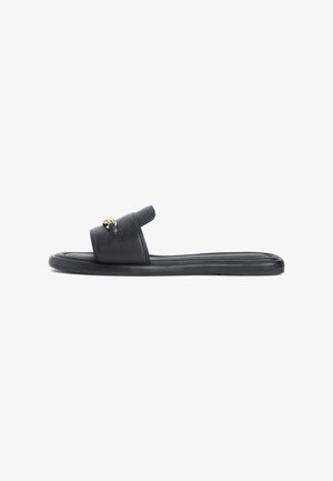 Black leather slide sandals with a flat sole, featuring a decorative gold metal accent on the strap. Smooth texture, minimalist design.