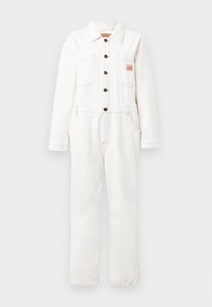 Bela denim kombinezona z dolgimi rokavi, spredaj na gumbe, z dvema žepoma na prsih in oblikovanim pasom. Odkrit šiv in detajl s krpicami.