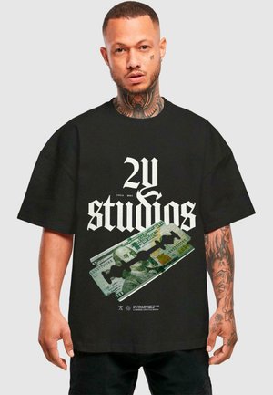 Black oversized t-shirt featuring bold white text “2U studios” and a graphic of a hundred-dollar bill with a razor blade illustration.