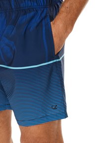 Short de bain bleu marine à motif de palmier et rayures horizontales dans différentes nuances de bleu. Taille élastique avec poches latérales.