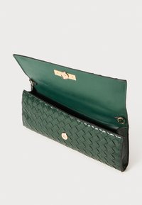 Grüne geflochtene Leder-Clutch mit einem glatten Innenraum, verfügt über einen goldenen Druckverschluss und ein strukturiertes Außendesign.
