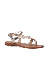 Flad sandal i metallisk rosaguld med krydset remme og dekorative teksturerede detaljer. Har en tåpost og træsål.