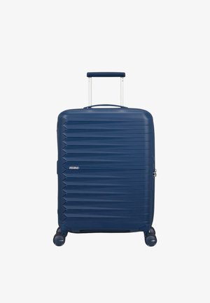 Valigia rigida blu navy con righe verticali, manico retrattile e quattro ruote a 360 gradi. Presenta un'etichetta con il logo sul davanti.