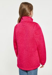 Fleece pulóver v jasne ružovej farbe s vysokým golierom, textúrovanou tkaninou a rovnom lemom. Dlhé rukávy a voľný strih.