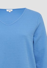 Blauwe gebreide top met een V-hals, textuurpatroon en lange mouwen. De stof lijkt licht van gewicht en is geschikt voor casual kleding.
