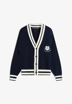 Cárdigan azul marino abotonado con ribete de rayas blancas en el cuello, los puños y el dobladillo, con el logotipo bordado de Tommy Hilfiger en el pecho izquierdo.