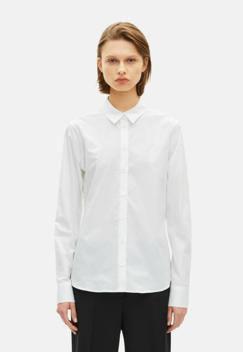 White long-sleeve shirt with a classic collar, button front, and embroidered detail on the chest; made of smooth cotton fabric.