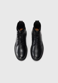 Black leather ankle boots with a smooth finish, featuring laces, a side zipper, and rounded toes. Stitched detailing around the sole.