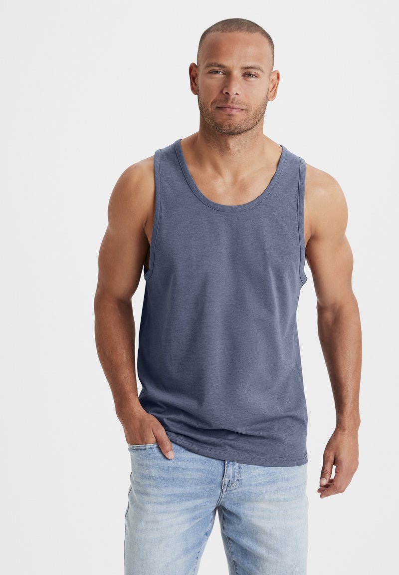 Navy blue tank top made of soft fabric, featuring a round neckline and sleeveless design. Worn with light blue jeans.