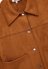 Giacca in suede marrone con colletto, bottoni a pressione e due tasche anteriori. Texture morbida con dettagli di cucitura ben visibili.
