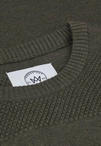 Maglione a maglia verde oliva con collo a girocollo a coste. Motivo texture sulle spalle, con un'etichetta bianca che mostra un logo e l'anno di fondazione.