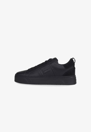 Zapatilla negra de cuero bajo con superficie texturizada, suela gruesa, cierre de cordones en la parte delantera y pequeño parche rectangular con logo en el lateral.