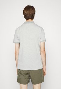 Grå och vit randig polo t-shirt med korta ärmar, med en klassisk krage och en solid grå kant, ihop med olivgröna shorts.