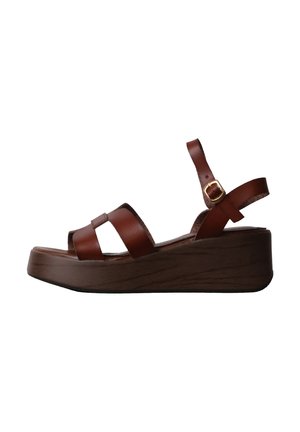 Sandale compensée en cuir marron avec semelle plateforme en bois et bride de cheville à boucle dorée, vue de côté sur fond blanc.