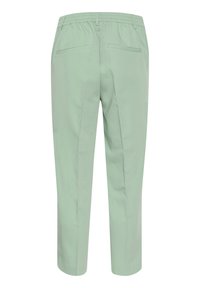 Pantaloni verde chiaro con vita elasticizzata, forma affusolata, tessuto liscio e due tasche posteriori, caratterizzati da un design semplice e pulito.