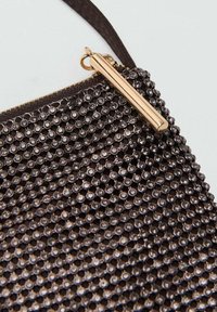 Pochette en perles noires avec fermeture éclair en métal doré, de forme plate, et surface texturée faite de nombreuses petites perles brillantes.