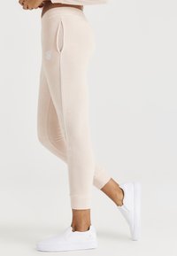 Leggings de forro de melocotón claro con bolsillos laterales, ribete blanco en contraste y un diseño ajustado, combinados con zapatos blanco de tipo slip-on.