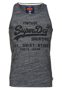 Camisa de tirantes de algodón gris con cuello redondo, diseño sin mangas y una audaz impresión gráfica negra que dice "Vintage SuperDry" en japonés.