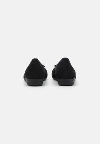 Scarpe di pelle scamosciata nera con punta rotonda e suola bassa e ammortizzata. Presentano una superficie liscia e un design minimalista, senza hardware visibile.