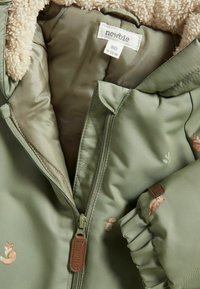 Groene jas met een zachte beige fleece voering, voorzien van dierenborduurwerk en een ritsluiting. Inclusief een stoffen label met de merknaam "newbie."