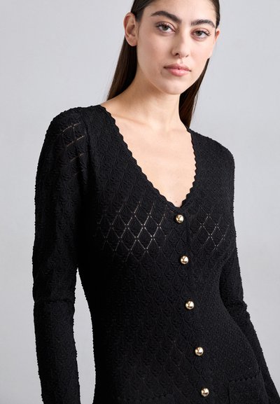 Zwarte cardigan met een gestructureerd breisel in een diamanten patroon, lange mouwen en gouden knopen aan de voorkant. V-hals.