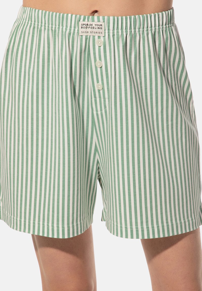 Groene en witte gestreepte boxers gemaakt van zachte stof, met een knoopsluiting aan de voorkant en een elastische tailleband met een klein label.