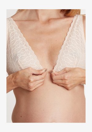 Lace beha in zacht beige met een diepe V-halslijn, voorzien van golvende randen en een sluiting aan de voorkant. Textuurstof met ingewikkelde bladdessins.