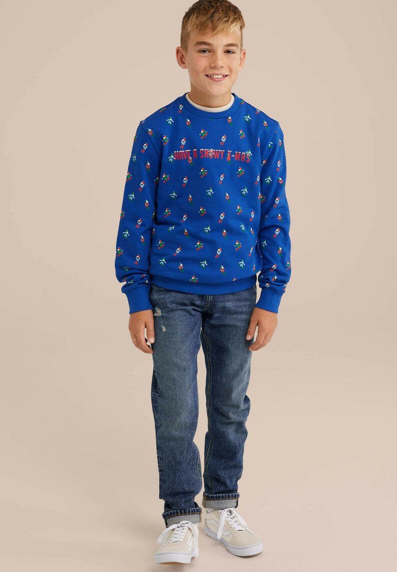 Modra sweatshirt z prazničnimi vzorci in napisom, v kombinaciji z denim hlačami in belimi supergami. Mehek material z rebrastimi manšetami in robom.