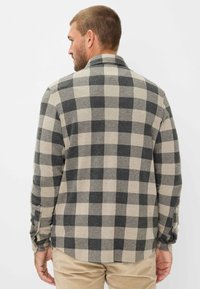 Herres flannel skjorte med et stort sort og beige ternet mønster, blød tekstur, knaplukninger ved manchetterne og krave, vist fra ryggen.