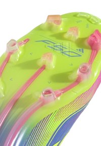 Cleat sole in vibrant yellow with bluish accents. Features transparent studs and pinkish translucent elements, enhancing grip and traction.