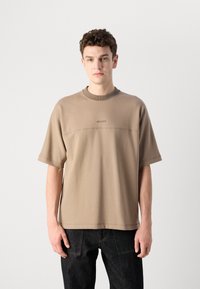 Light brown short-sleeve t-shirt with a ribbed neckline and embossed logo on the chest. Casual cut, made from soft fabric.