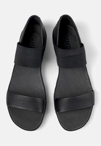 Svarta sandaler med breda elastiska remmar, en slät läderliknande ovandel och en strukturerad sula. Designade för lätt påtagning och komfort.