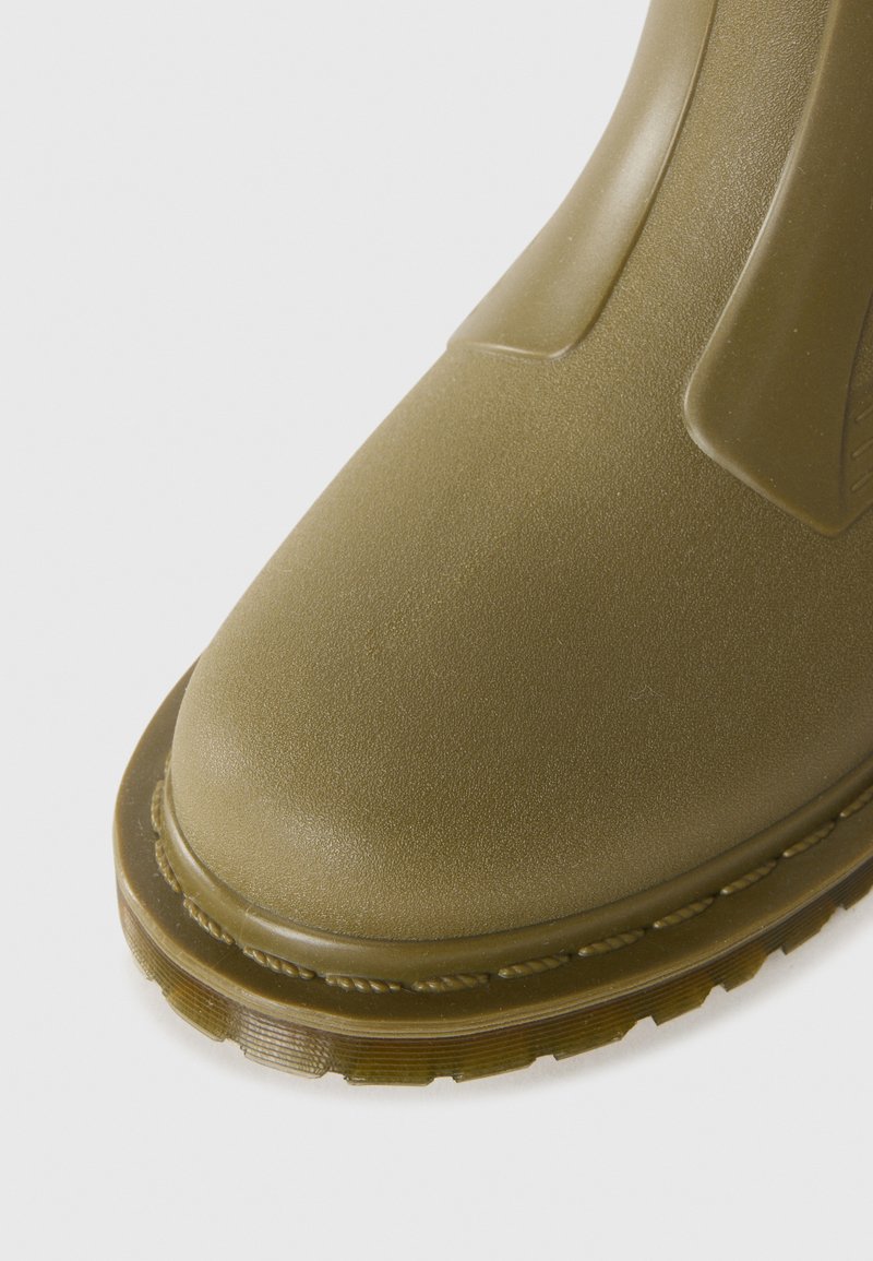 Green rubber boot with a rounded toe, textured upper, and a thick treaded sole. Seamless design with minimal detailing and a matte finish.